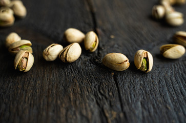 Pistachios scattered on the wooden vintage table. Pistachio is a healthy vegetarian protein nutritious food. Pistachios on rustic old wood.