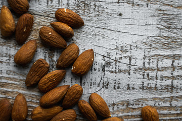 Almonds scattered on the wooden vintage table. Almond is a healthy vegetarian protein nutritious food. Almonds on rustic old wood.