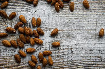 Almonds scattered on the wooden vintage table. Almond is a healthy vegetarian protein nutritious food. Almonds on rustic old wood.