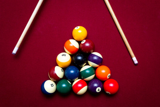 Billiard balls racked in a triangle on a red felt pool table