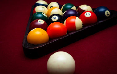 Close up of pool balls racked in a triangle on a red felt table