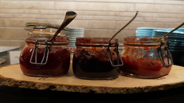 Three small pots with jam at breakfast buffet of Finnish restaurant, closeup shot. Small spoons placed into open little jars for self serving of traditional Lapponian sweet products