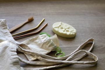 Canvas tote bag with zero waste products: menstrual cup, soap, reusable straws and bamboo toothbrush. Selective focus.