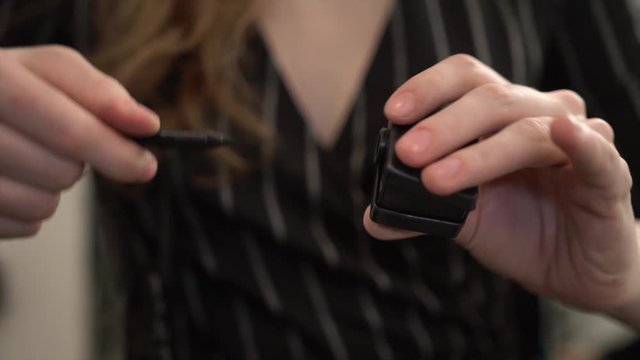 Professional makeup artist&rsquo;s hands rotates black eyeliner in dual makeup pencil sharpener. Visagiste keeps the eye pencil in shape before applying it on client's eyelids to create perfect cat eye look