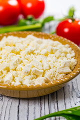 Feta Crumbled Cheese with Spinach and Tomatoes on White Wooden Background. Selective focus.