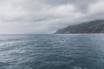 Norwegian fjord and mountains surrounded by clouds, ideal fjord reflection in clear water. selective focus.