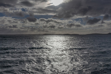 A mystical fjord in Norway with mountains and fog hanging over the water in polar day. midnight sun, selective focus