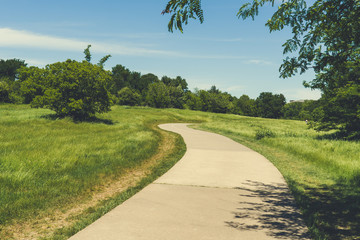 Concrete walkway in Texas city natural park on a sunny spring day.