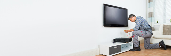 Technician Installing TV Set Top Box At Home