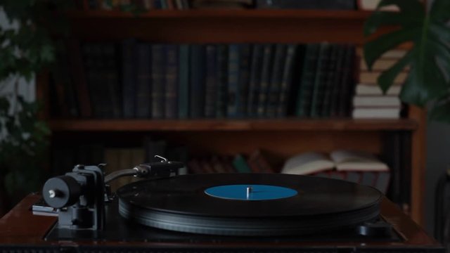 Man in white shirt turns off retro record player, removes the needle from record, selective focus
