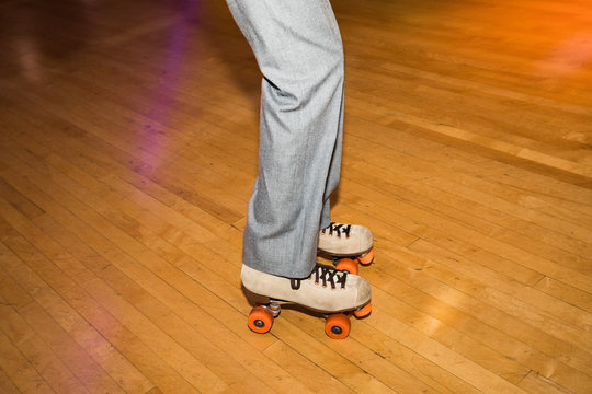 Legs of people roller skating in a wood skate ring.