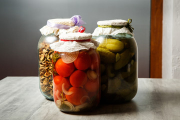 three big clear glass jar with colorful pickled vegetables served on wooden table