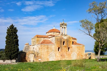 Fototapeta na wymiar Metamorphosis Sotiros church in Pylos Nestor Palace (Niokastro Navarino) and trees in Greece at sunny day