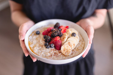 Healthy breakfast brunch oatmeal. Healthy lifestyle. Fruits and berries. Strawberry, raspberry, blackberry, blueberry, banana. Maple syrup drizzle. Cinnamon topping. White plate. Weekday breakfast