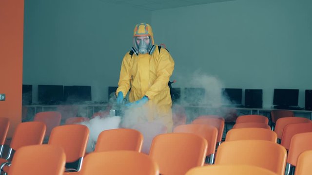 A disinfection worker sanitizer chairs with a sprayer.