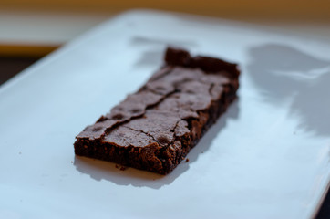 Homemade brownie on white plate. Brownie on black counter. Brownie with decoration. Brownie with smiley.