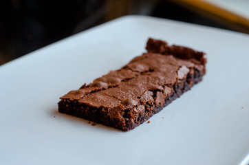 Homemade brownie on white plate. Brownie on black counter. Brownie with decoration. Brownie with smiley.