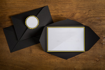 top view closeup on pile of black envelopes with white invitation space