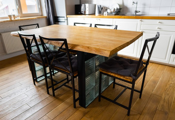A big wooden dining table with glass blocks and metal wicker chairs and pillows in modern...