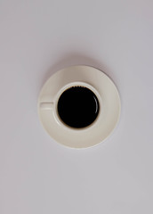 Minimalist white cup of coffee with plate on pink background with copy space on its sides. White background. Isolated cup of coffee on white background.