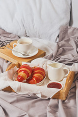 Breakfast in bed, coffee with cream, croissants in jam