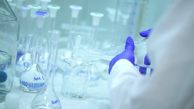 doctor chemist mixing pouring transparent liquid chemical in flask on table Spbd. a lot of beakers in pharmaceutical laboratory. group of measuring cylinders in analyzing development