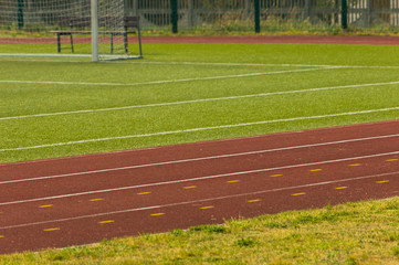 Athletics stadium. Outdoor athletics treadmill running track lines with behind football gate.