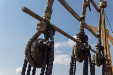 Block and tackle rigging on an old tall ship before blue sky, spliced and wrapped rope lines,...