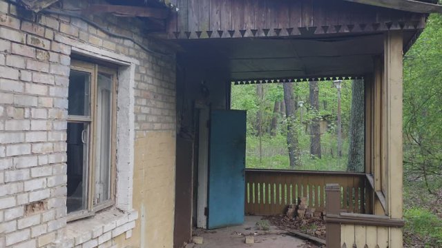 Abandoned haunted house with a wooden veranda in a green spring forest. Aerial low angle close-up view