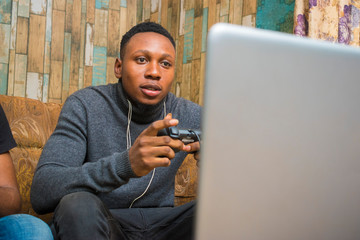 young handsome african man seriously playing game on his laptop