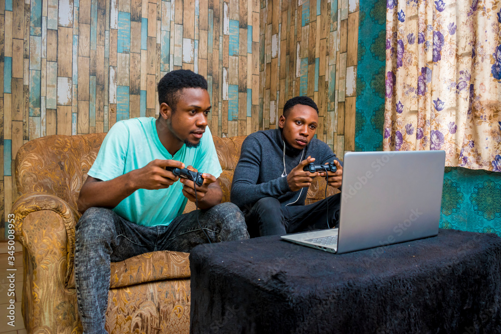 Wall mural young black men playing a video game on a laptop at home