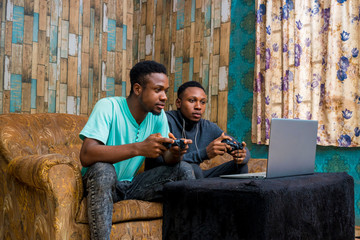 young black men playing a video game on a laptop at home