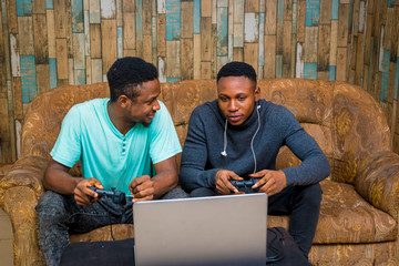 young black men playing a video game on a laptop at home