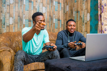 young black men playing a video game on a laptop at home