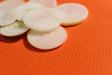 Fototapeta na wymiar Onion slices on orange chopping board