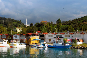 Fototapeta na wymiar TRABZON, TURKEY - SEPTEMBER 24, 2009: Fishing Shelter, Boats, Mosque and Buildings. Of District