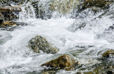 Rapid flowing water in mountain river stream. Foam flow water splash natural waterfall wild nature background


