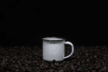 Mug with coffee over coffee beans