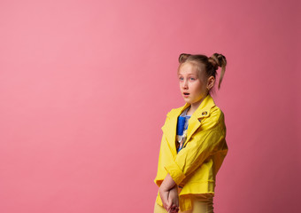 young lady stands with her mouth open looking surprised at empty space on a pink background in yellow clothes