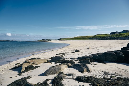 Landscape of the Omey Island surrounded by the sea under the sunlight and a blue sky in Ireland