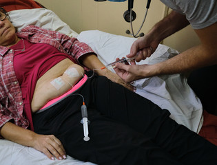 a physician doing a subcutaneous vial for the treatment of an adult woman with covid-19 during the pandemic