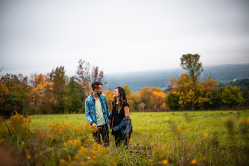 Happy young couple in love walking outside colorful fall leaves