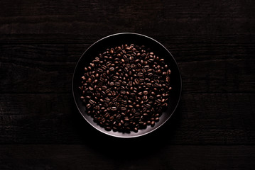 
Coffee beans in a plate on a wooden board.