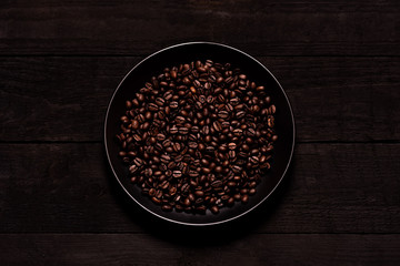 
Coffee beans in a plate on a wooden board.