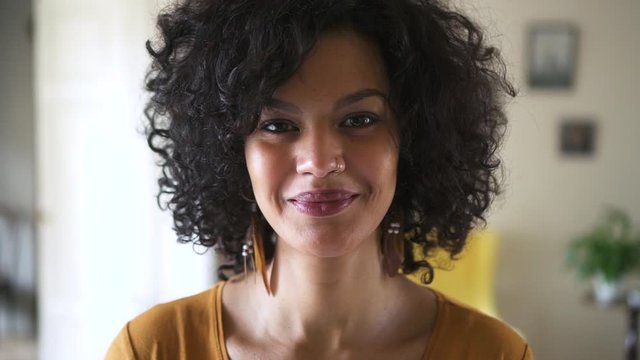 portrait of casual smiling confident female fashion model in home interior Spbd. strong feminine biracial woman looks at camera with happy expression. concept afro curly