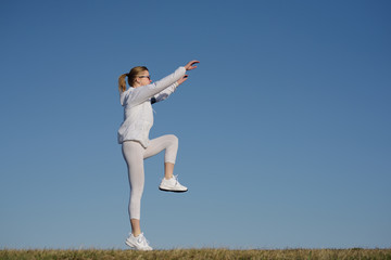 Fitness woman jumping outdoor. Adult woman in sportswear exercising in morning.