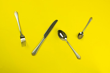 set of cutlery on a yellow background. tableware. silverware and stainless steel. The concept of food, lunch, breakfast and dinner. fork, knife, spoon.