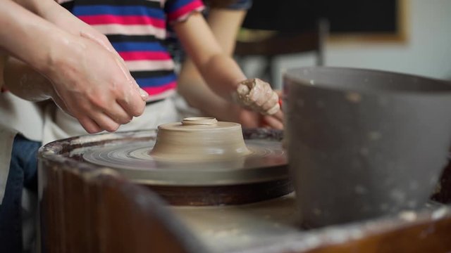 Close up of Hands of Child Making Ceramic Pot with Help of Art Techer. Little Girl Working on a Pottery Wheel in a Workshop. Craft and Clay Art, Child Creative Education Activities