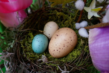 Colorful ornamental bird eggs in moss covered craft bird nest