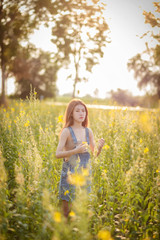 Beautiful Asian woman standing on the sunhemp flowers field on sunny summer or spring day.